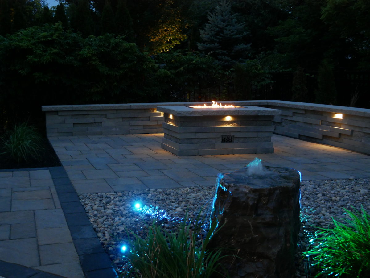 stone patio at night with fire pit and blue night lights
