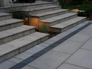 side view of stone stairs with greenery behind yard lighting