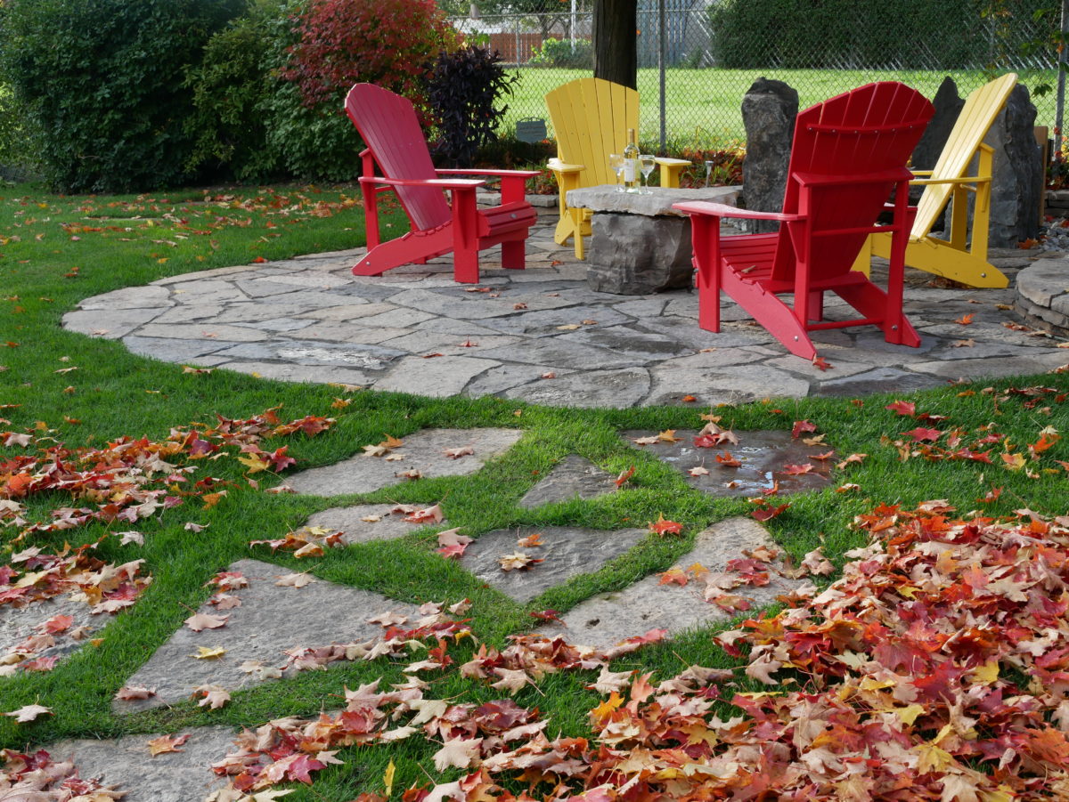 red and yellow coloured chairs surrounding a stone table with fall leaves